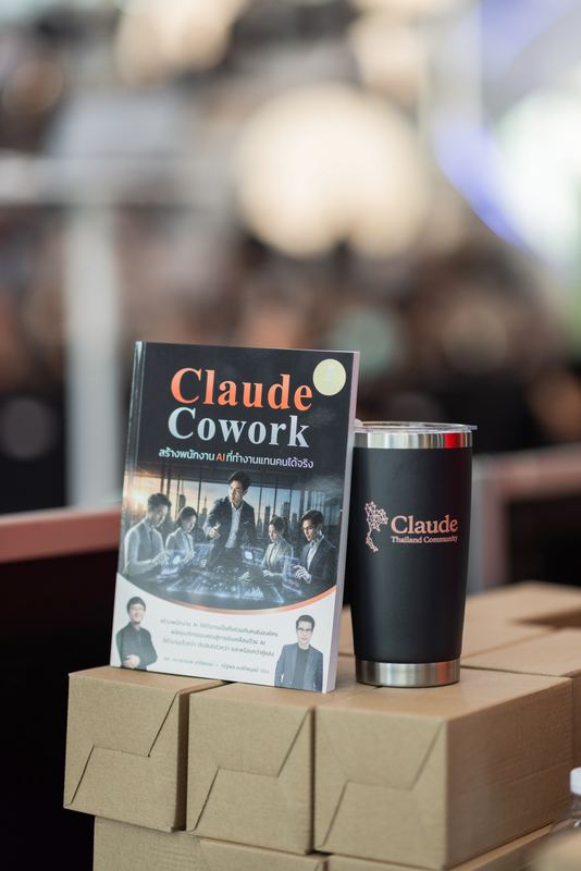 หนังสือ Claude Cowork และแก้ว Claude Thailand Community วางบนกล่อง