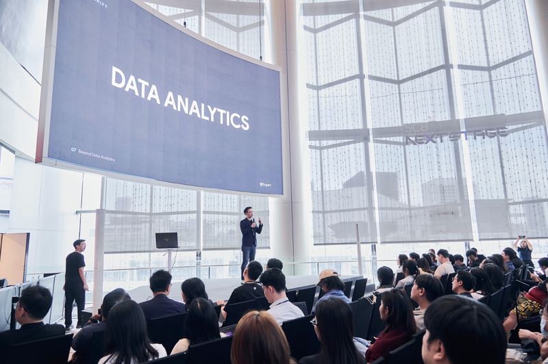 อ.ชไลเวทบรรยายบนเวที จอขนาดใหญ่ด้านบนขึ้นคำว่า DATA ANALYTICS ผู้ฟังนั่งเต็มพื้นที่