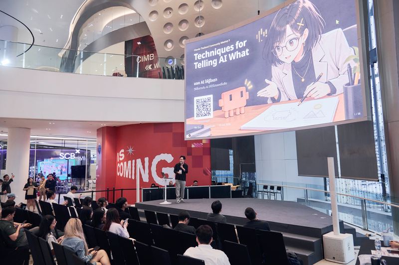 คุณศิระบรรยายบนเวที จอด้านบนแสดงสไลด์เปิดหัวข้อ Techniques for Telling AI What You Really Want